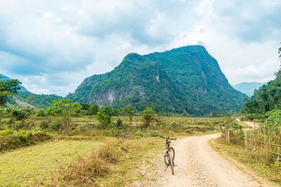 Dirt road by mountain against sky