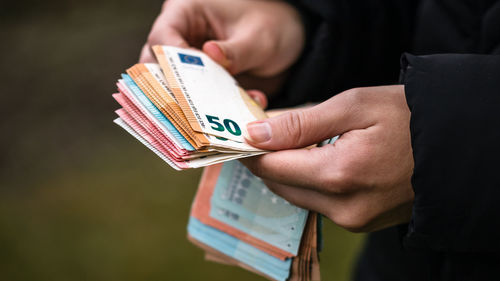 Midsection of man holding paper currency