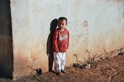 Portrait of boy standing against wall