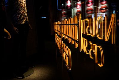 Low section of person holding illuminated glass at night