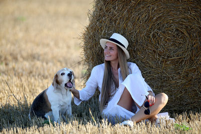 Woman with dog sitting on field