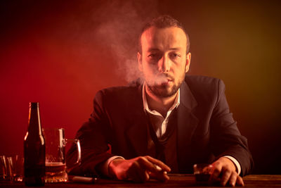 Portrait of a young man drinking glass on table