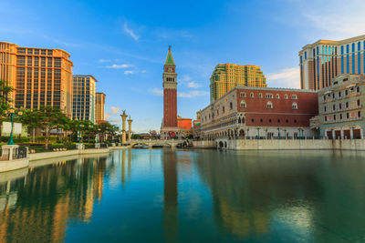 Reflection of buildings in lake against blue sky