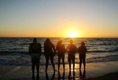 People standing on beach during sunset