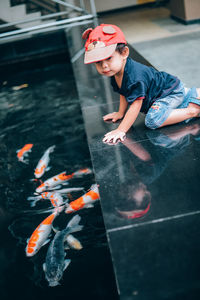 Cute girl looking at fishes in swimming pool