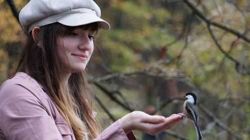 Portrait of young woman feeding a bird