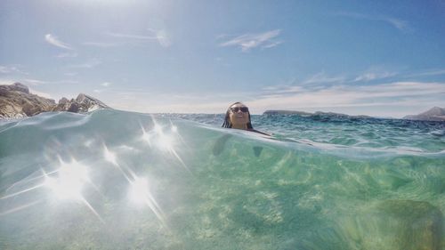 Mature woman swimming in sea against sky