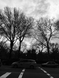 Cars on road against cloudy sky