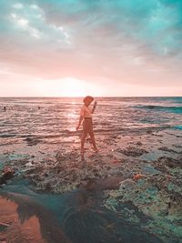 Man standing on beach against sky during sunset