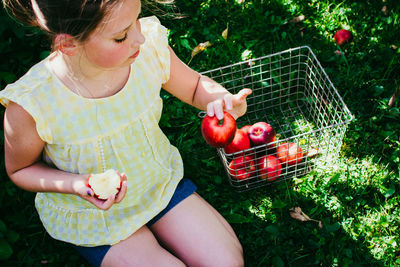 Girl having apple while kneeling in yard