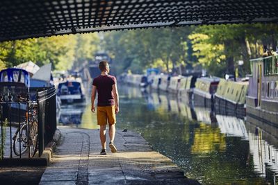 Rear view of man walking on wet road during rainy season