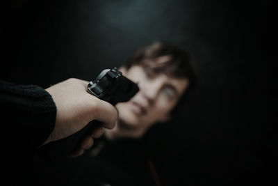 Close-up portrait of young man holding camera over black background