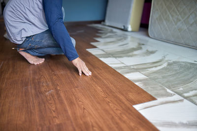 Low section of man working on hardwood floor at home