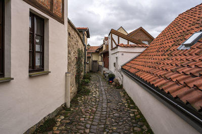 Alley amidst houses and buildings against sky