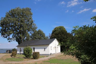 House on field by trees against sky