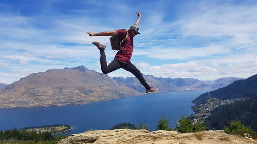 Full length of man jumping on mountain against sky