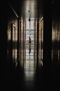 Full length of woman standing in long narrow corridor