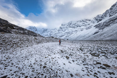 Rear view of man hiking on rock formation against sky