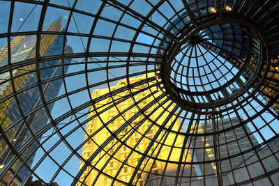 Low angle view of sky and buildings seen through glass ceiling