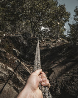 Cropped hand holding rope on mountain