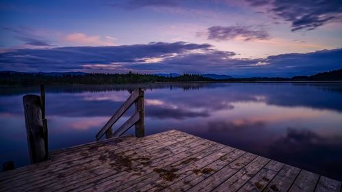 Pier over lake against sky during sunset