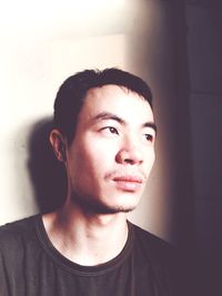Portrait of young man standing against wall at home