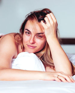 Portrait of young woman lying on bed at home