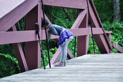 Side view of girl standing on wooden camel back bridge