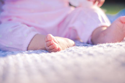 Low section of baby lying on bed