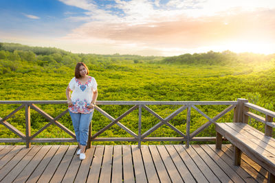 Man standing on railing against sky