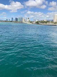 Sea by buildings in city against sky