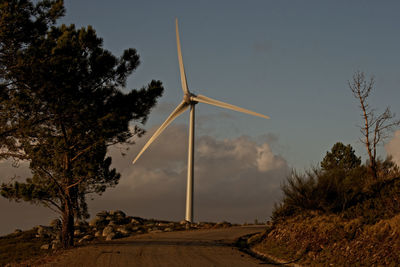 Low angle view of wind turbines on landscape against sky