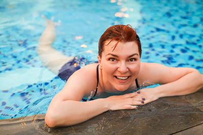 Portrait of a smiling young woman swimming in pool