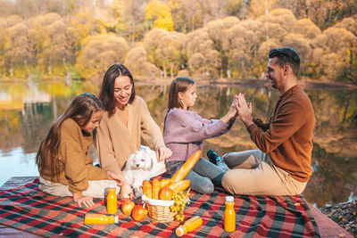 Rear view of people sitting at beach during autumn