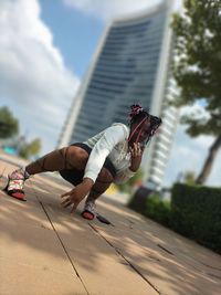 Low angle view of young woman infront of a high rise building 