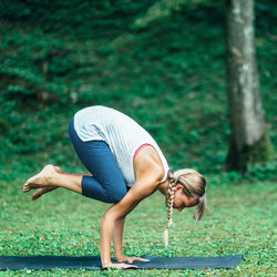 Full length of woman practicing bakasana in park