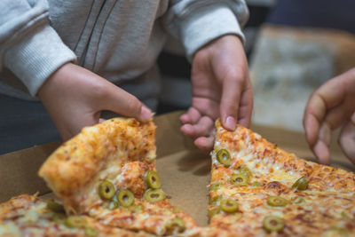 Close-up of hands taking pizza from box