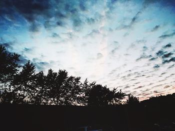 Low angle view of silhouette trees against cloudy sky