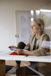Businesswoman looking away while using digital tablet at home