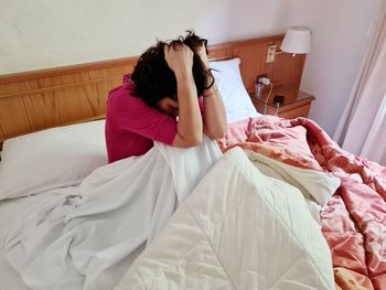 Young woman using mobile phone while lying on bed at home