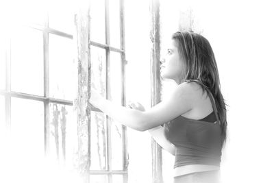 Side view of young woman looking through window