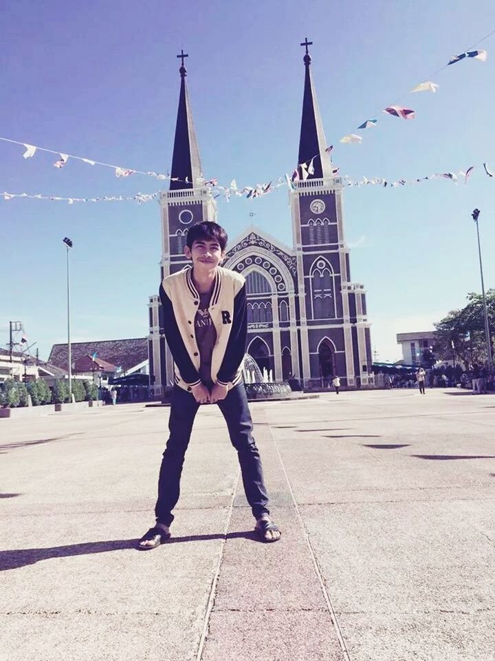 building exterior, lifestyles, leisure activity, young adult, built structure, architecture, standing, front view, religion, casual clothing, portrait, sky, looking at camera, spirituality, person, place of worship, full length