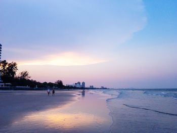 Silhouette people on beach against sky during sunset