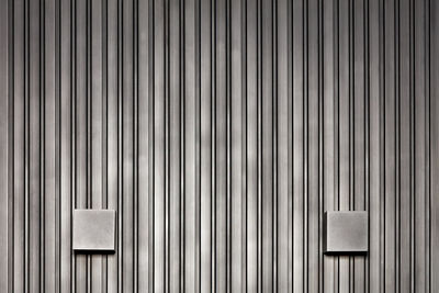 Stylish wall lights and wood wall with black silver vertical rails.
