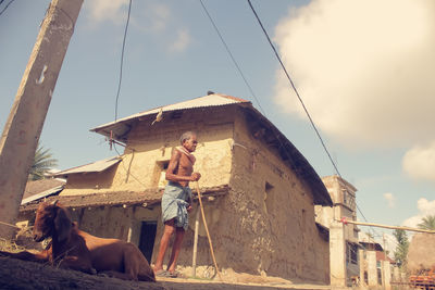 Low angle view of woman standing on building against sky