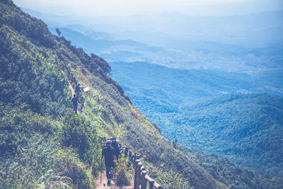Rear view of people walking on mountain range against sky