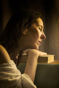 Woman in a white blouse with a carmen neckline with her hands resting on an old book 