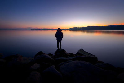 Man looking at sea against sky during sunset