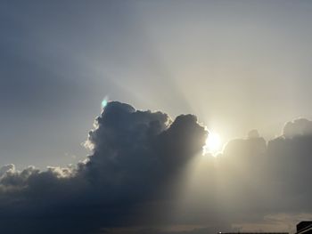 Low angle view of sunlight streaming through clouds