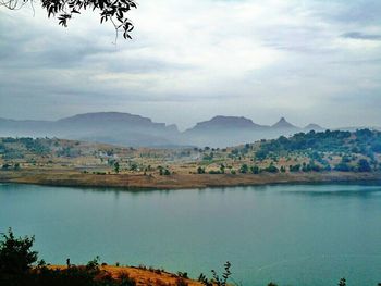 Scenic view of lake and mountains against cloudy sky